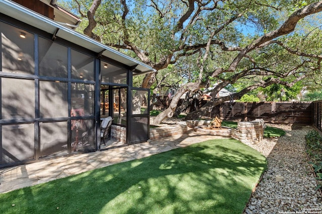 view of yard featuring a fire pit, a sunroom, and a patio