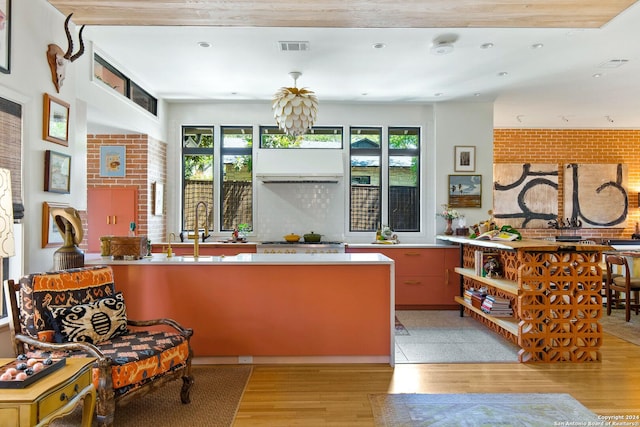 kitchen with brick wall, light hardwood / wood-style floors, and a wealth of natural light