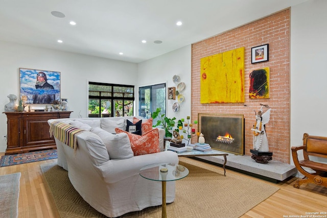 living room featuring wood-type flooring and a brick fireplace