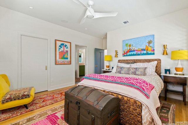 bedroom with ceiling fan, connected bathroom, and hardwood / wood-style flooring