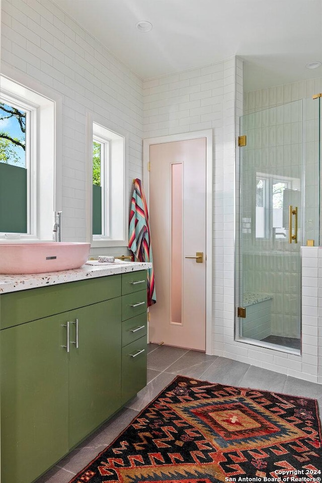 bathroom with tile walls, walk in shower, vanity, and tile patterned floors