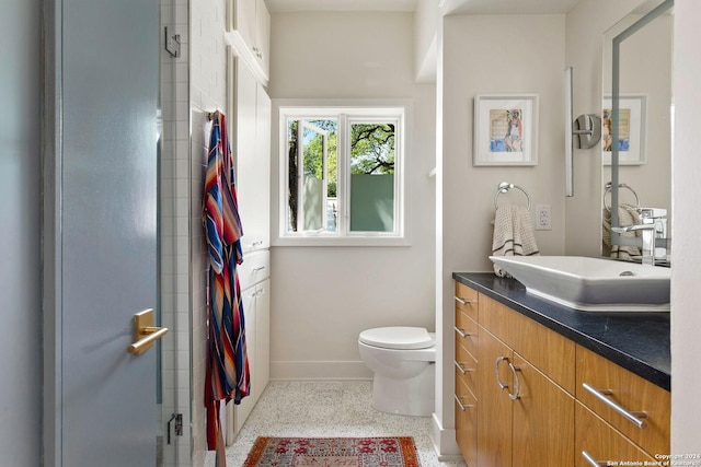 bathroom with walk in shower, vanity, and toilet