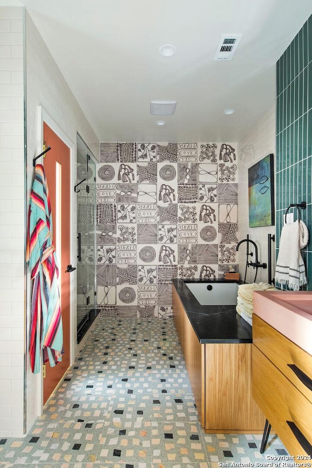 bathroom with vanity, tile walls, and a shower with shower door