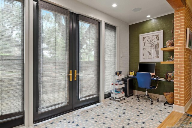 office area featuring built in desk, french doors, hardwood / wood-style floors, and brick wall