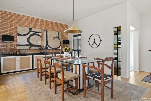 dining space featuring light hardwood / wood-style floors and brick wall