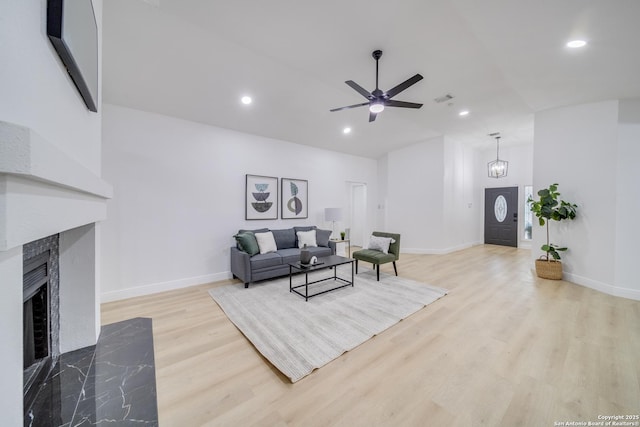 living room with a fireplace, ceiling fan, and light hardwood / wood-style floors