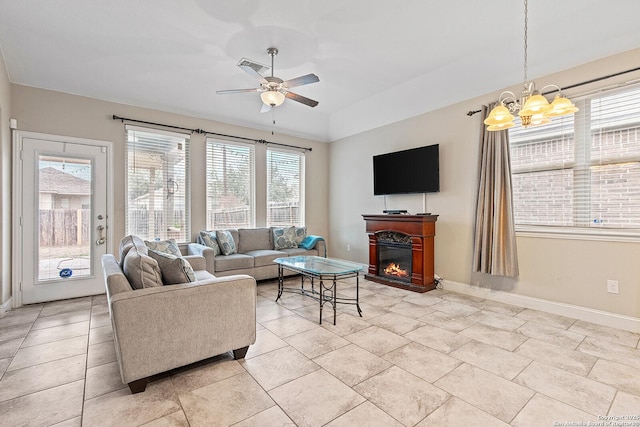 living room with ceiling fan with notable chandelier and plenty of natural light