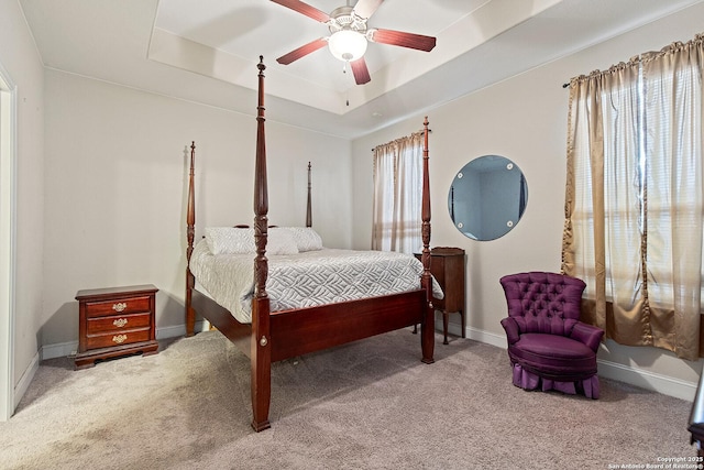 carpeted bedroom with a raised ceiling and ceiling fan