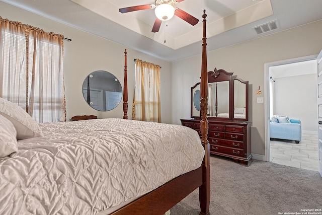 carpeted bedroom featuring a raised ceiling and ceiling fan