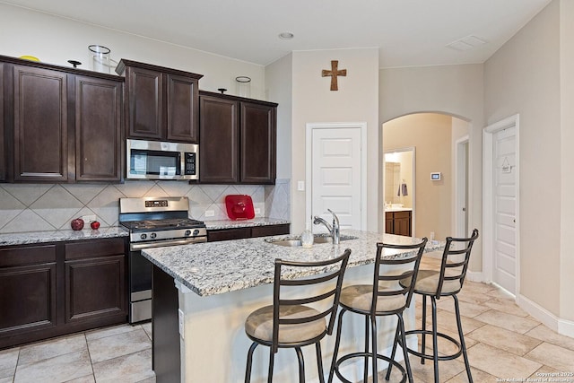 kitchen with a center island with sink, appliances with stainless steel finishes, a breakfast bar, sink, and dark brown cabinets