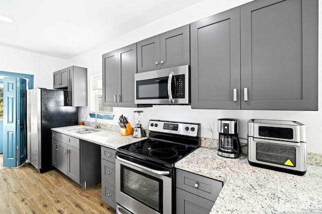 kitchen featuring sink, stainless steel appliances, gray cabinets, and light stone countertops