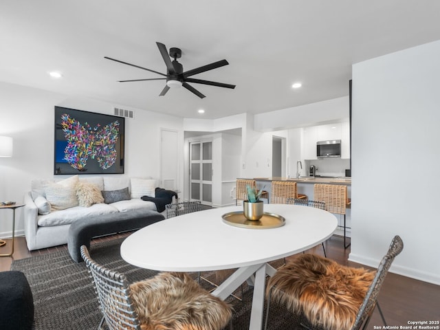 dining space featuring sink, dark wood-type flooring, and ceiling fan