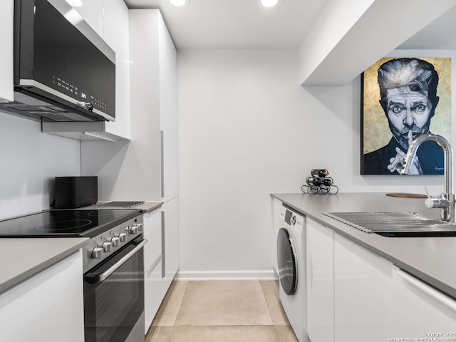 kitchen with electric stove, washer / dryer, white cabinetry, light tile patterned flooring, and sink