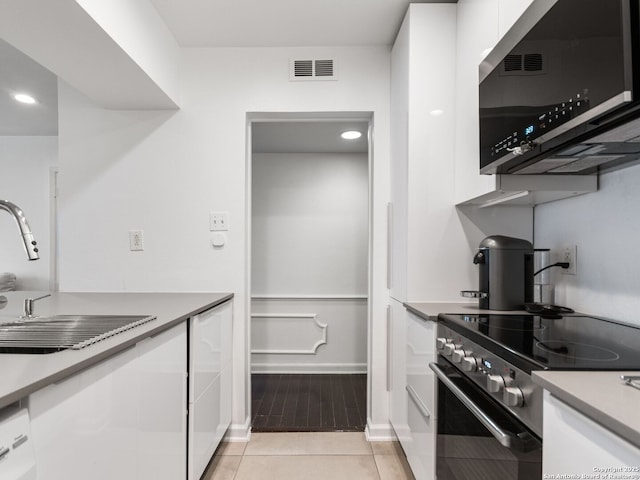 kitchen with white cabinets, appliances with stainless steel finishes, light tile patterned floors, and sink