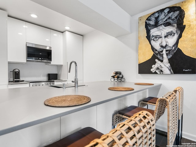 kitchen featuring sink, white cabinetry, and range