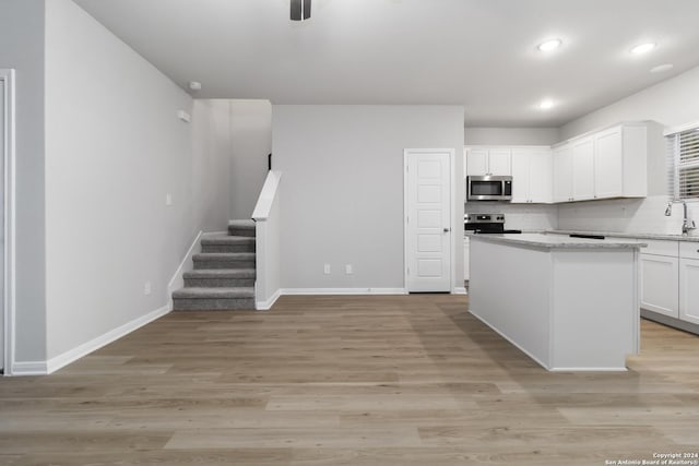 kitchen featuring appliances with stainless steel finishes, white cabinetry, backsplash, and a kitchen island