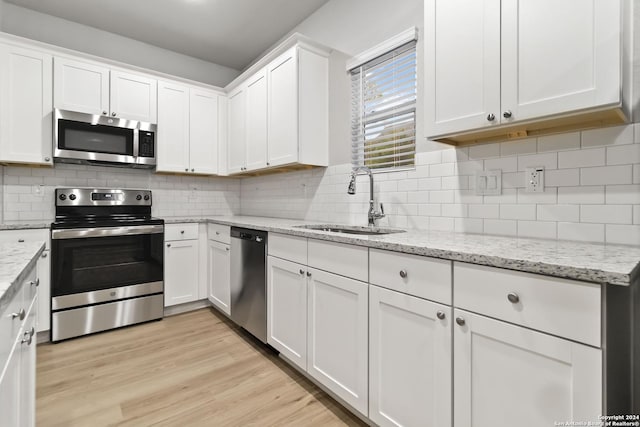 kitchen with sink, white cabinetry, light stone counters, decorative backsplash, and appliances with stainless steel finishes