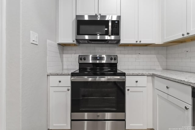 kitchen with light stone counters, stainless steel appliances, white cabinets, and decorative backsplash