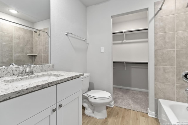 full bathroom featuring toilet, hardwood / wood-style flooring, tiled shower / bath, and vanity