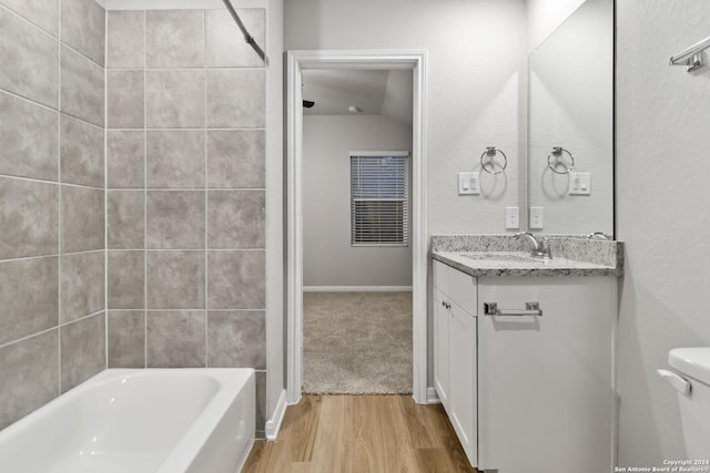 full bathroom featuring toilet, hardwood / wood-style flooring, tiled shower / bath, and vanity