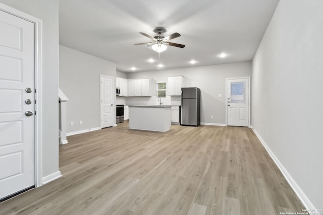 kitchen with stainless steel appliances, a center island, ceiling fan, white cabinets, and light hardwood / wood-style flooring