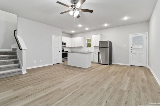 kitchen with appliances with stainless steel finishes, light wood-type flooring, a center island, ceiling fan, and white cabinets