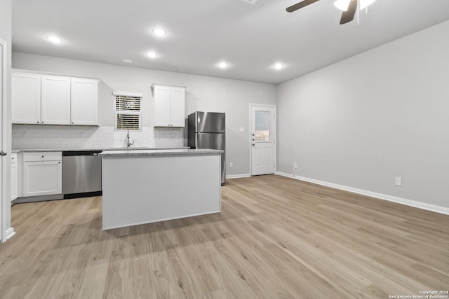 kitchen with stainless steel appliances, a center island, backsplash, and white cabinetry