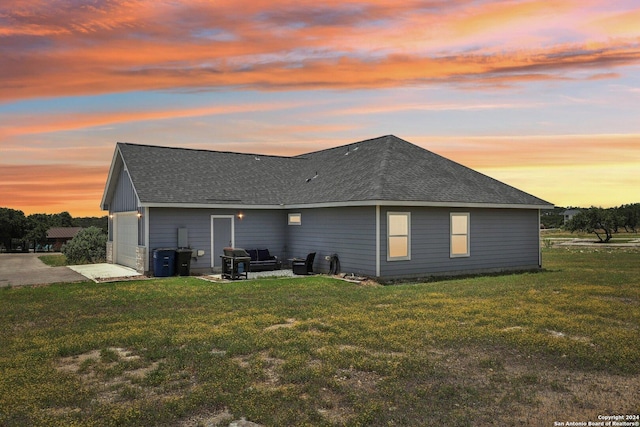 back house at dusk with a yard and a garage