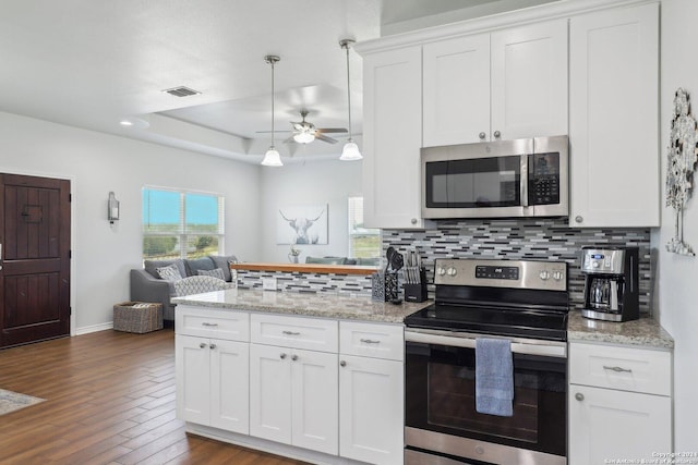 kitchen featuring white cabinets, stainless steel appliances, and a raised ceiling