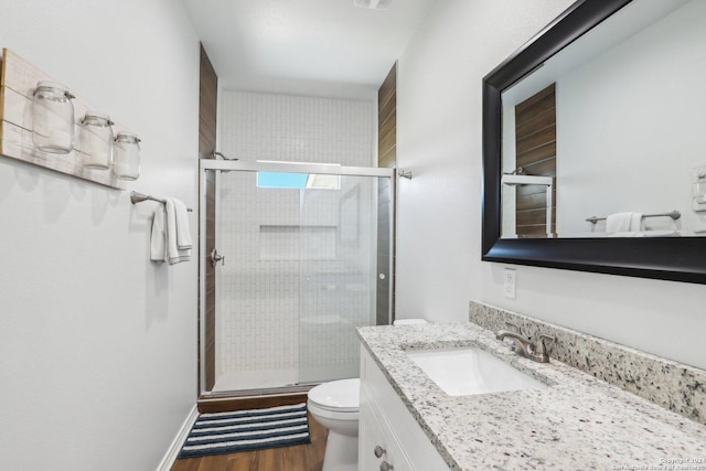 bathroom featuring wood-type flooring, vanity, a shower with shower door, and toilet