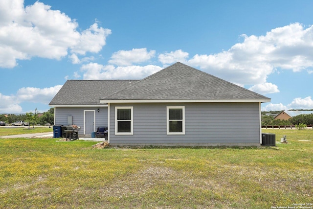 rear view of property with central AC unit and a lawn