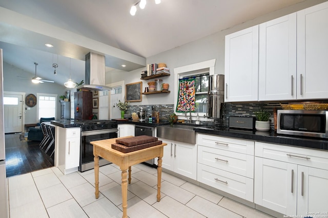 kitchen featuring gas range oven, lofted ceiling, island exhaust hood, and decorative backsplash