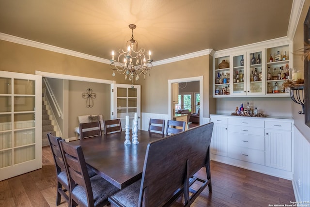 dining area with dark wood-type flooring, french doors, a notable chandelier, and ornamental molding