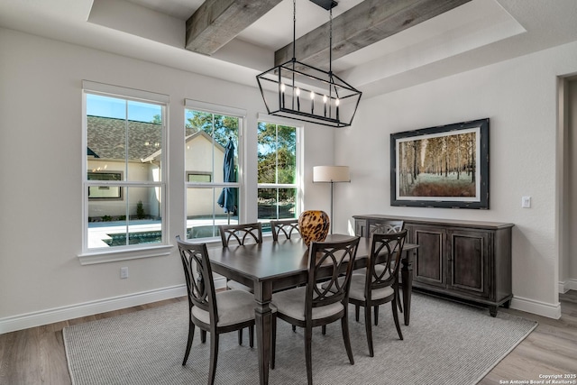 dining area with light hardwood / wood-style floors, a chandelier, and beamed ceiling