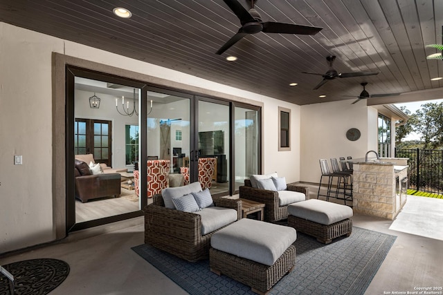 view of patio / terrace with a bar, ceiling fan, and an outdoor living space