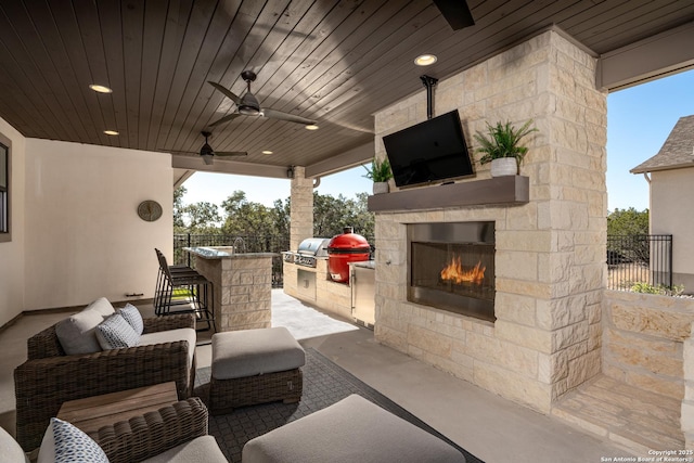 view of patio with an outdoor bar, an outdoor kitchen, an outdoor stone fireplace, ceiling fan, and a grill