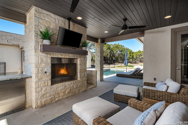 view of patio / terrace featuring ceiling fan and an outdoor living space with a fireplace