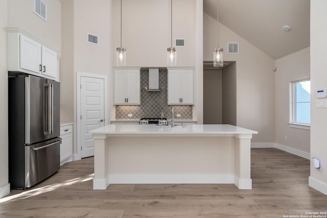 kitchen with decorative light fixtures, high quality fridge, tasteful backsplash, and white cabinets