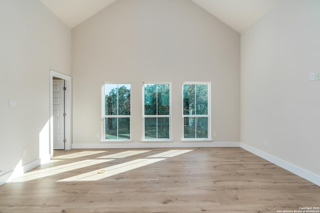 empty room featuring high vaulted ceiling and light hardwood / wood-style flooring