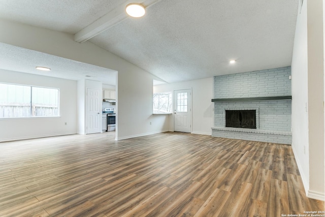 unfurnished living room featuring a textured ceiling, a brick fireplace, lofted ceiling with beams, and wood-type flooring