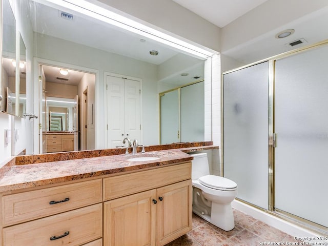 bathroom featuring toilet, a shower with shower door, and vanity