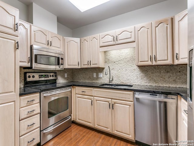 kitchen featuring light wood-type flooring, appliances with stainless steel finishes, backsplash, and sink