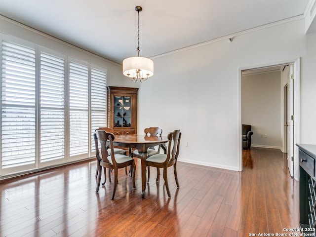 dining area featuring ornamental molding, dark wood-type flooring, and a notable chandelier