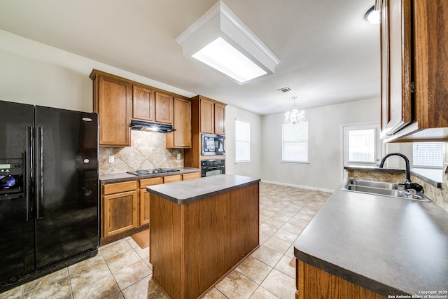 kitchen with a center island, decorative light fixtures, a notable chandelier, black appliances, and sink