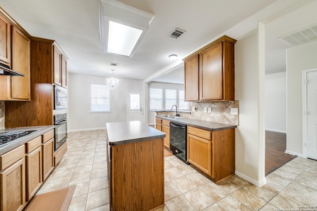 kitchen featuring pendant lighting, backsplash, a kitchen island, a chandelier, and black appliances