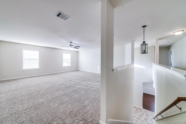 carpeted spare room with ceiling fan with notable chandelier