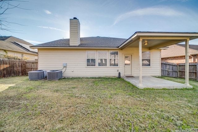 back of property with central AC, a patio area, and a lawn