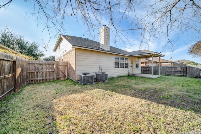 rear view of property featuring central air condition unit, a patio area, and a lawn