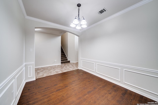 spare room featuring dark hardwood / wood-style flooring, crown molding, and a chandelier