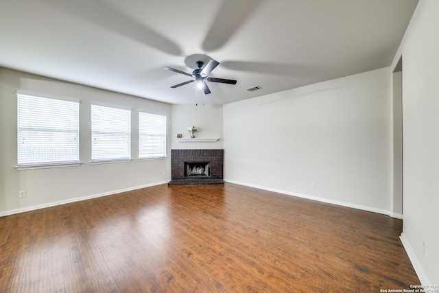 unfurnished living room with dark hardwood / wood-style flooring, a brick fireplace, and ceiling fan